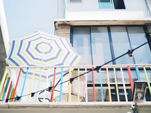 a balcony with a colorful umbrella on a window at The Sugar Hostel in Ban Sai Ma