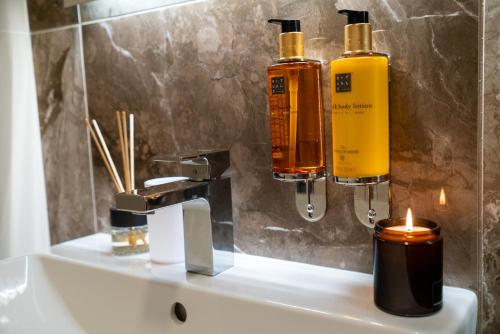 a bathroom sink with two bottles of soap and a candle at apartino - free parking v okolí - in the neighbourhood, city view balcony, nespresso, netflix in Komárov