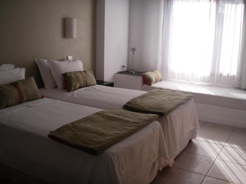 a hotel room with two beds and a window at Posada de los Pajaros in Punta del Este