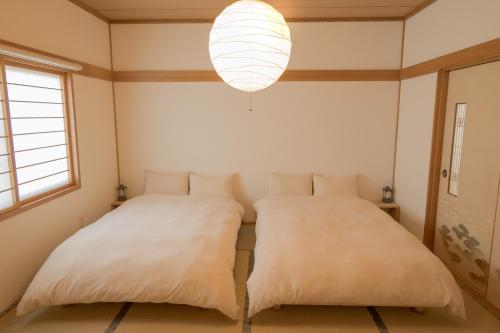 due letti in una stanza con un lampadario di Mother River Stays -Stream Inn Shibetsu- Vacation Home, Gateway to Shiretoko & Nemuro Strait a Shibetsu