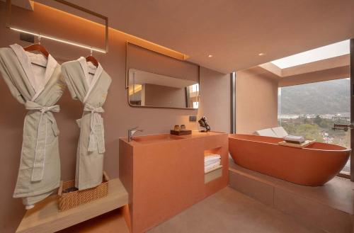 a bathroom with a tub and a sink and a mirror at Zhangjiajie Shisuji Hotel (Zhangjiajie National Forest Park Sign Gate Branch) in Zhangjiajie