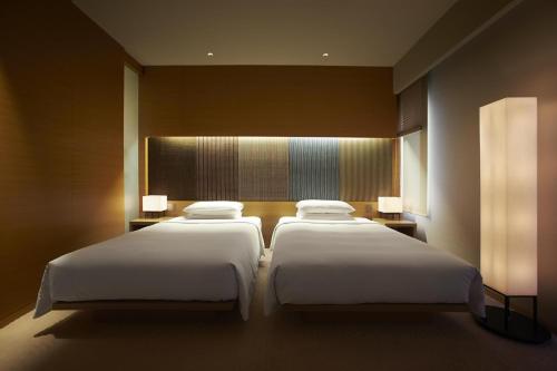 two beds in a hotel room with two lamps at Hyatt Regency Kyoto in Kyoto