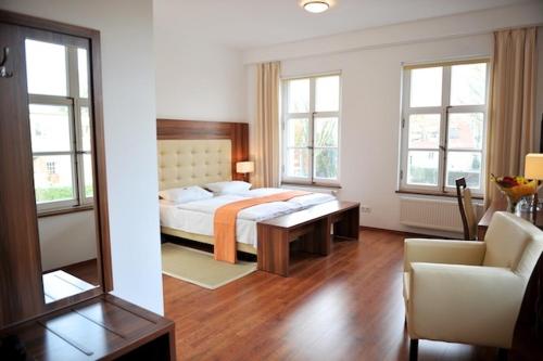 a bedroom with a bed and a chair and a mirror at Akzent Hotel Tietmeyer & Cross Side in Schöppingen