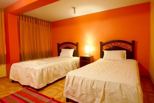 two beds in a room with orange walls at Olimpo Inn in Puno