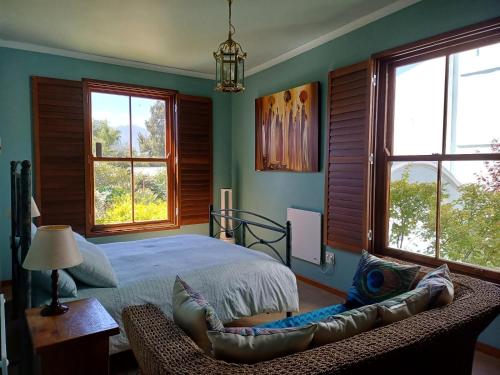 a bedroom with a bed and a couch and windows at Pool House at the Old Victorian in Tulbagh