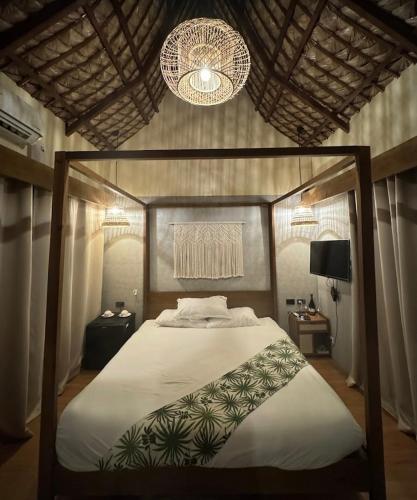 a bedroom with a canopy bed with two chandeliers at Querencia Resort in Porac