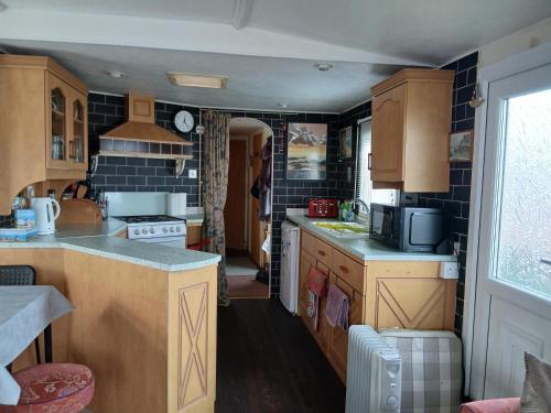 uma cozinha com armários de madeira e uma bancada em Charming 6 Berth Caravan With Decking By The Beach In Suffolk Ref 40107Nd em Gunton