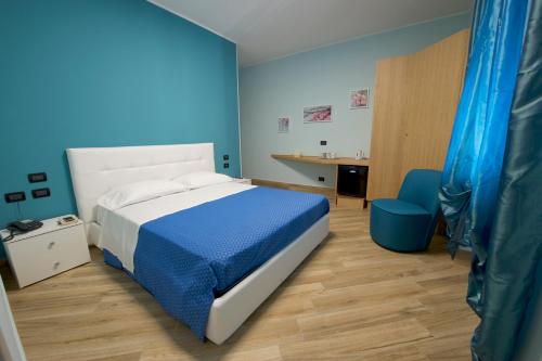 ein blaues Schlafzimmer mit einem Bett und einem Schreibtisch in der Unterkunft Relais Piazza Garibaldi in Terracina