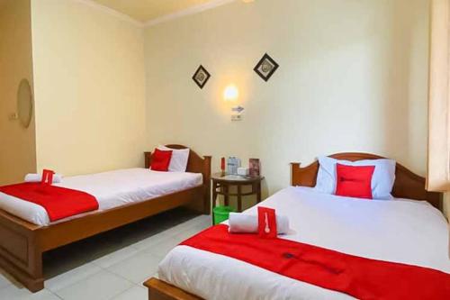 a bedroom with two beds with red and white sheets at RedDoorz Syariah near T1 Juanda Airport 2 in Surabaya