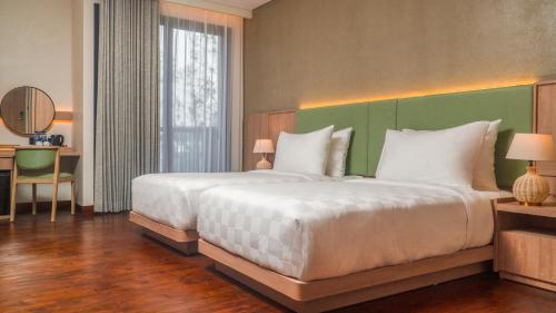 a bedroom with a large white bed with a green headboard at Jambuluwuk Bromo Resort in Pasuruan
