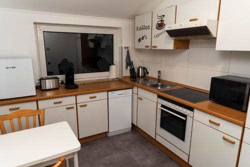 eine Küche mit weißen Schränken und einer Spüle in der Unterkunft Strandnahe Ferienwohnung Nordsee Oase Whg. 1 in Cuxhaven