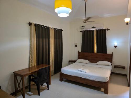 Un dormitorio con una cama, una mesa y un escritorio. en Coastal Suites Apart Hotel ---- 12 minutes walk to beach, en Benaulim