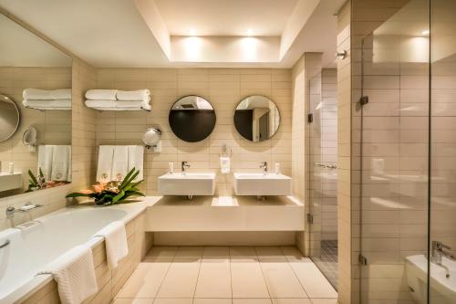 a bathroom with two sinks and a tub and mirrors at Labadi Beach Hotel in Accra