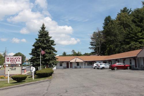 a motel with cars parked in a parking lot at Wagon Wheel Inn in Lenox