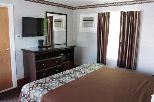 a bedroom with a bed and a dresser and a television at Wagon Wheel Inn in Lenox