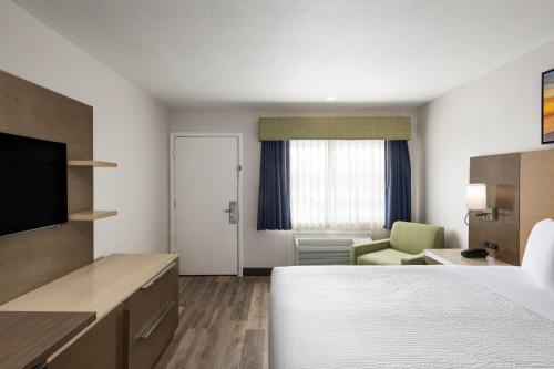 a small hotel room with a bed and a chair at Days Inn by Wyndham Monterey Downtown in Monterey