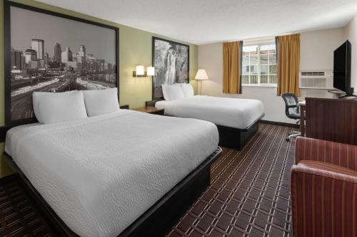 una habitación de hotel con dos camas y un escritorio en Super 8 by Wyndham Winona MN, en Winona