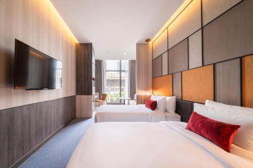 a hotel room with two beds and a flat screen tv at Ramada Plaza by Wyndham Bangkok Sukhumvit 48 in Bangkok