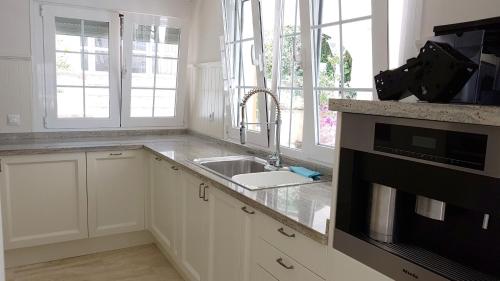 Una cocina blanca con fregadero y microondas. en Casa Jolanda, en La Caleta