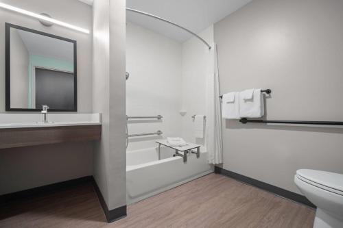 a bathroom with a sink and a toilet and a mirror at ECHO Suites Extended Stay by Wyndham Johnson City Medical CR in Johnson City