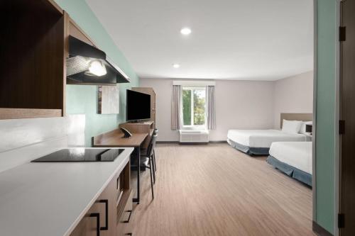 a hotel room with a kitchen and a bed and a room at ECHO Suites Extended Stay by Wyndham Johnson City Medical CR in Johnson City