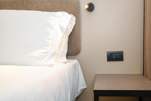 a bed with a white pillow next to a table at Hotel Garda in Affi