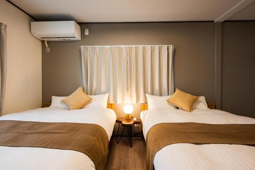two beds in a small room with a window at Ojanse博多 in Fukuoka