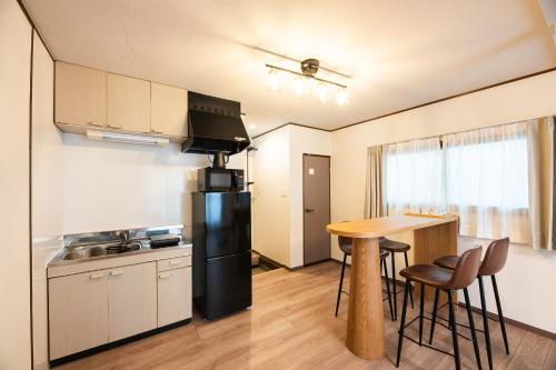 a kitchen with a black refrigerator and a table at Ojanse博多 in Fukuoka