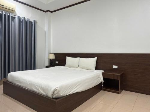 une chambre avec un grand lit avec des draps blancs dans l'établissement Avenue Hotel VangVieng, à Vang Vieng