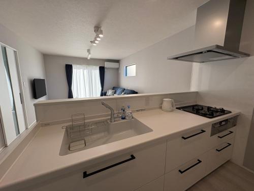 une cuisine blanche avec un évier et une cuisinière dans l'établissement 縁-Takasaki, à Takasaki