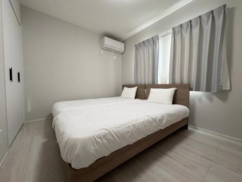 une chambre avec un lit avec des draps blancs et une fenêtre dans l'établissement 縁-Takasaki, à Takasaki