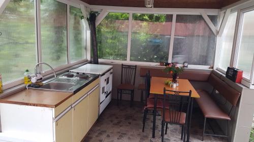 cocina con mesa y fregadero y algunas ventanas en Oaza Mira Mozgovo, en Mozgovo
