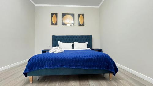 a bedroom with a blue bed with two pillows at Athletic City, 1-Room Apartments in Taldykolʼ