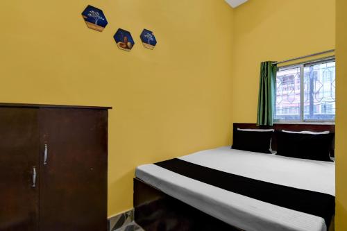 1 dormitorio con 1 cama y una ventana con sombreros en la pared en Hotel O Madhyamgram Railway Junction Formerly Dreamland, en Dohāri