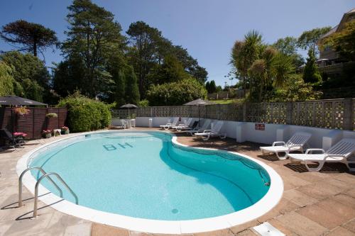 einen Pool mit Liegestühlen und Stühlen um ihn herum in der Unterkunft Bourne Hall Country Hotel in Shanklin