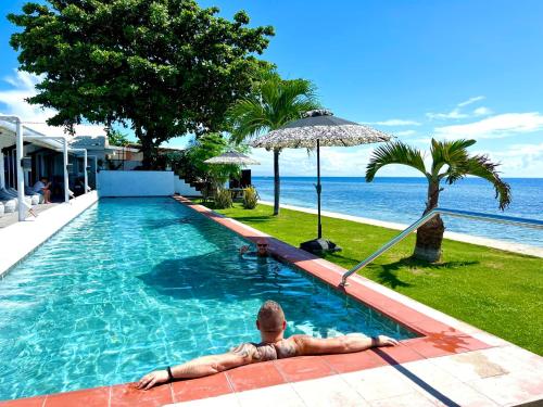 a man laying in a swimming pool next to the ocean at the beachhouse cebu in Dalaguete