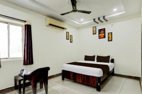 a bedroom with a bed and a chair in it at OYO Hotel O Benz Circle Vijayawada in Vijayawāda