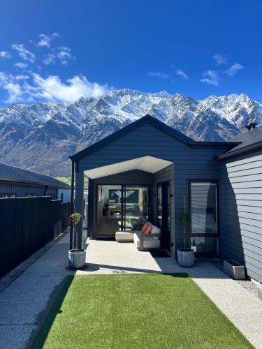 ein blaues Haus mit Bergen im Hintergrund in der Unterkunft 3Bedroom 2Bathroom Golf Skiing Hiking Lake Mountains 7 Min To Airport in Queenstown