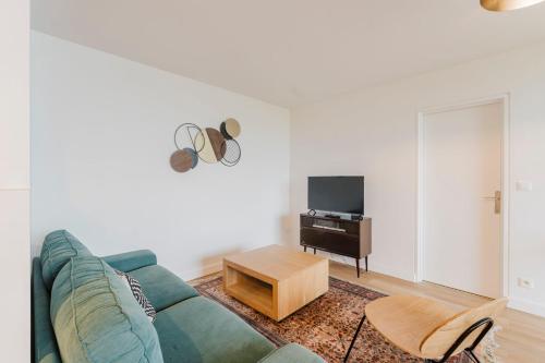 ein Wohnzimmer mit einer grünen Couch und einem Tisch in der Unterkunft Charming apartment 2ch 4p parking and balcony in La Madeleine