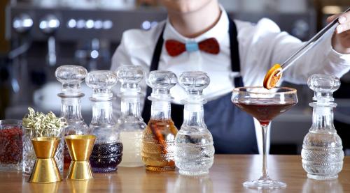 a bartender is preparing a drink in a line of glassutes at Athens Tiare by Mage Hotels in Athens