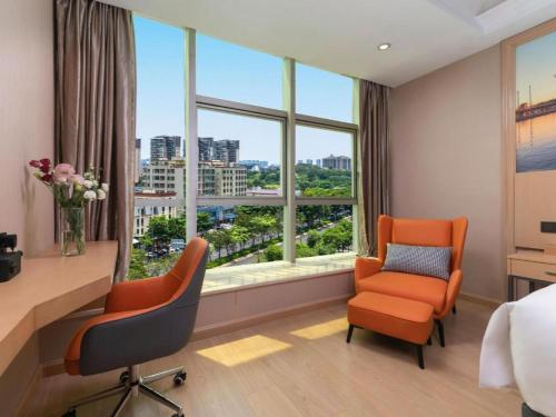 ein Hotelzimmer mit Schreibtisch, zwei Stühlen und Fenster in der Unterkunft Vienna Hotel Shenzhen International Exhibition Center Fuhai Qiaotou in Fenghuangwei