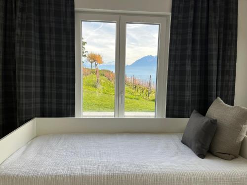 a bed in front of a window with a view at Renovated APT with panoramic view in Cully