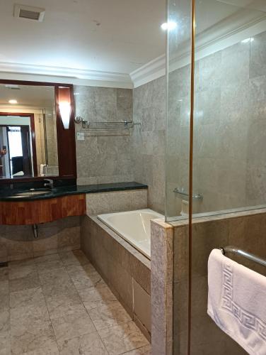 a bathroom with a tub and a sink and a mirror at Crown Suits At Times Square in Kuala Lumpur