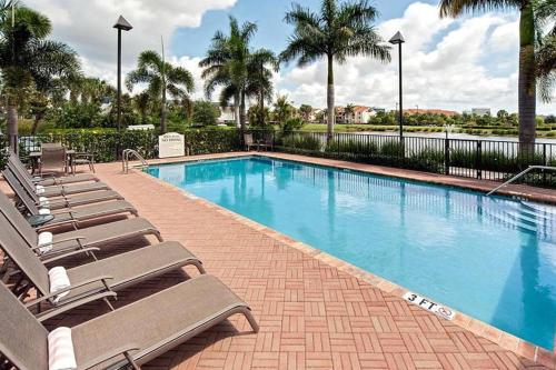 a swimming pool with lounge chairs and palm trees at Hawthorn Extended Stay by Wyndham West Palm Beach Airport in West Palm Beach