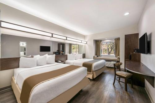 a hotel room with two beds and a television at Microtel Inn & Suites by Wyndham Pearl River/Slidell in Pearl River