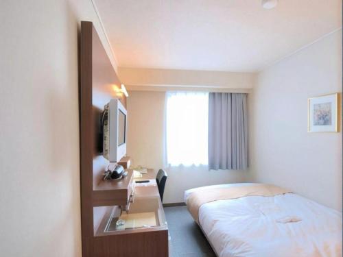 NuttariにあるNiigata Keihin Hotelのベッドと机があるホテルの部屋