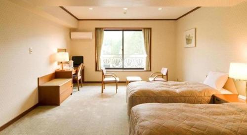 een hotelkamer met twee bedden en een bureau bij HOTEL WINDSOR in Nakatsugawa