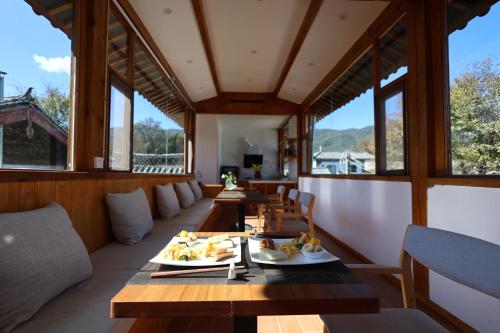 Un comedor con mesas y sillas y ventanas. en Lijiang Sadhu Inn, en Lijiang