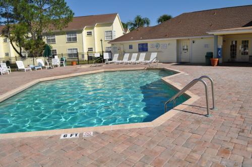 a swimming pool in a yard with chairs and a house at Villas at Laguna Bay in Kissimmee