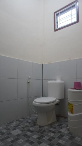 une salle de bain blanche avec toilettes et fenêtre dans l'établissement Homestay, à Labuan Bajo